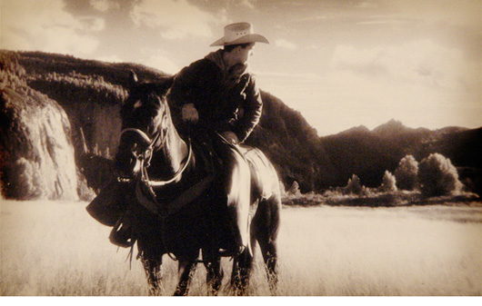 Cowboy on horse looking back by Myron Beck