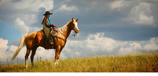 Cowgirl on Horse with dramatic sky behind