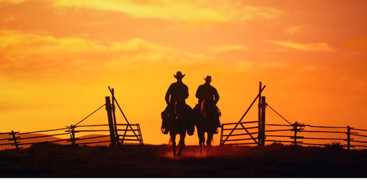 Beautiful photo of sunset with cowboys in foreground